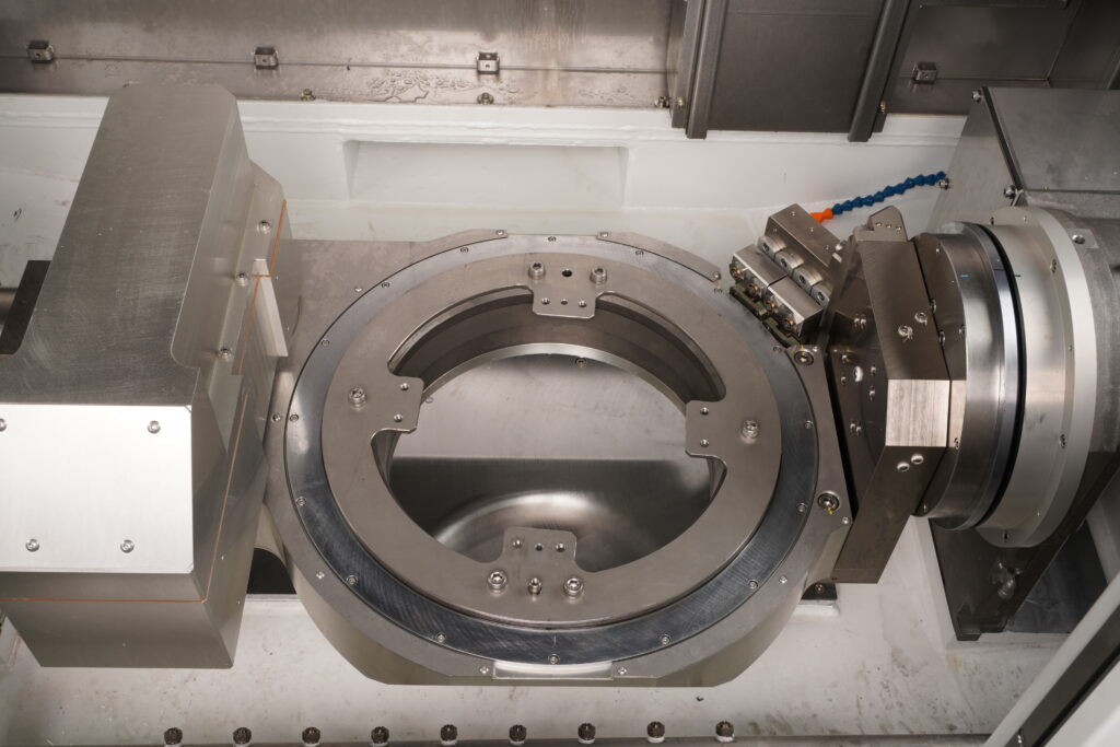 The rotary table in the Sugino JCC 104 Hybrid deburring and parts washing system allows access to all 6 sides of a part with indexing 3+2 axis